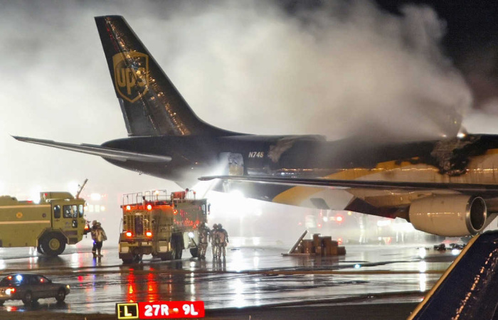 FILE - In this Feb. 8, 2006 file photo, firefighters battle a blaze onboard a UPS cargo plane at Philadelphia International Airport in Philadelphia. New U.S. government tests are raising concern that rechargeable lithium batteries carried as cargo on passenger airliners around the world are susceptible to fires or explosions that could destroy the planes. Yet U.S. and international officials have been slow to adopt safety restrictions that might affect both powerful industries that depend on the batteries and the airlines that profit from shipping them. The batteries are for products ranging from cellphones and laptops to hybrid cars. (AP Photo/Joseph Kaczmarek, File)